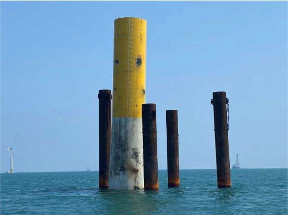 Caption: The fallen monopile, embedded in the seabed and listing at an angle above water.